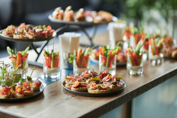 Lots of good food on the table. Small sandwiches on a black plate. Catering
