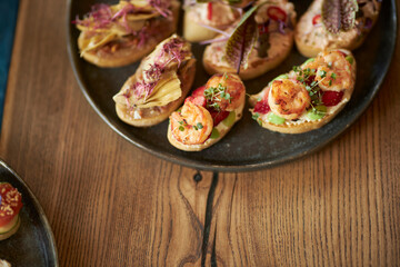 Small sandwiches on a black plate. Catering