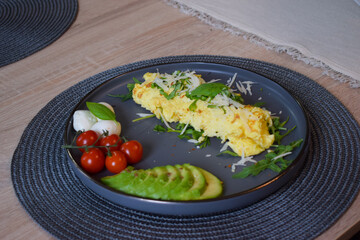 French omelette dish. Delicous homemade french omlette filled with cheese. Plating with fresh vegetables like avocado, cherry tomatoes, but also basil and mozzarella.