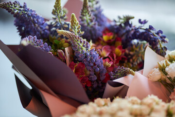 Bouquet of delicate flowers. Bouquet with purple elongated flowers on a blurred background.