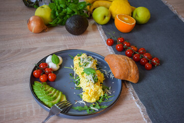 French omelette dish. Delicous homemade french omlette filled with cheese. Plating with fresh vegetables like avocado, cherry tomatoes, but also basil and mozzarella.