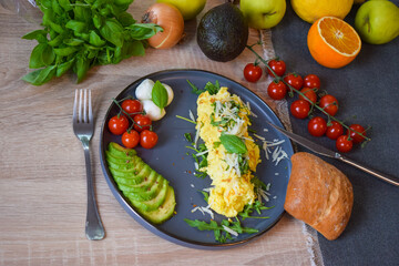 French omelette dish. Delicous homemade french omlette filled with cheese. Plating with fresh vegetables like avocado, cherry tomatoes, but also basil and mozzarella.