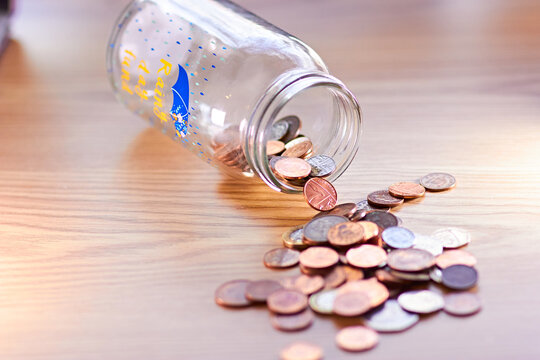 Rainy day fund savings jar pouring english coins onto a table