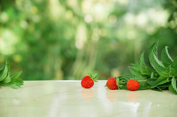 Fresh ripe delicious strawberries and mint on a gray stone and green background