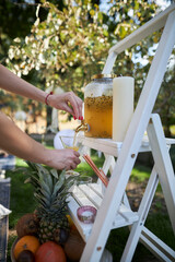 girl at a garden party pouring orange juice from a glass dispenser
