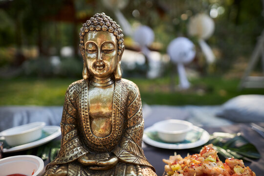 Bronze Buddha figurine in nature, at a picnic, close-up of the Buddha figurine