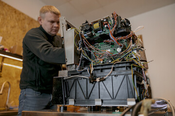 Male electrician repairing coffee machine in workshop