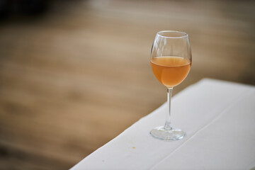 A glass of wine is on the table. Outdoors. 