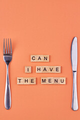 Wooden cubes with the inscription Can I have the menu and cutlery. Flat lay composition on color background.