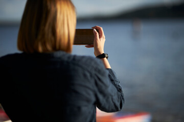 The girl photographs the river on the phone. The girl communicates via video link.