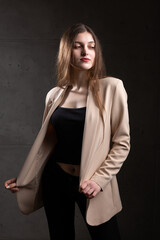 Portrait of a young brunette with long hair in the studio. Dramatic photo in dark colors.