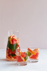 Grapefruit juice with green mint on beige background. Cocktail fresh grapefruit and lime juice combined with tequila. Two glasses of grapefruit lemonade. Refreshing summer drinks. vertical. copy space