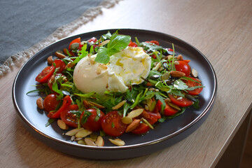 Burrata Salad with Cherry Tomatoes, Rucola, Basil, Olive Oil and Balsamic Creme. Burrata fresh cheeses tastes amazing and can be served alongside tomatoes, grilled bread, or vegetables.