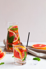 cocktail with fruits.Cocktail grapefruit with tequila. fresh Grapefruit juice with green mint on beige background. Glass and jug of grapefruit lemonade. Refreshing summer drinks. copy space. vertical.