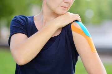 Woman with kinesio tape on her shoulder. Kinesiology, physical therapy, rehabilitation