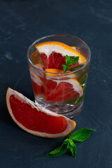 close-up Grapefruit lemonade with fresh fruits and green mint in a glass on black background. copy space. Refreshing summer drinks on the table. glass of Cocktail grapefruit.vertical