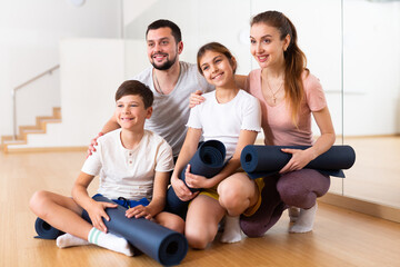Fototapeta na wymiar Happy family with rolled mats in gym. Kids and parents on yoga training.