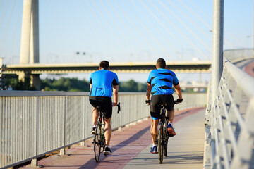 Sportive men cycling by Ada Bridge over the Sava river in Belgrade, Serbia, on hot summer day. Nice sport for active people. Healthy lifestyle.