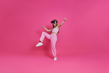 Full length of playful young woman in virtual reality headset having fun