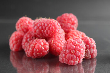 raspberries lie in a heap on a black background with a reflection. Vitamins seasonal berries freshness taste benefit. Raspberries for packaging labels