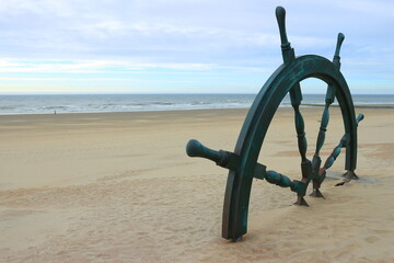Ein gro&szlig;es Steuerrad am Strand von Westende