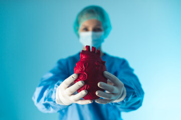 Medium studio shot over blue background of a female doctor dressed in blue scrubs holding an...