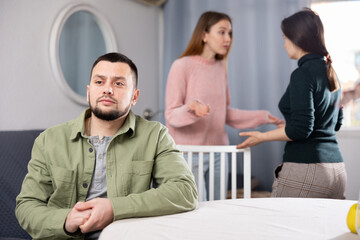 Displeased man waiting for two women relatives to calm down and stop quarreling at home