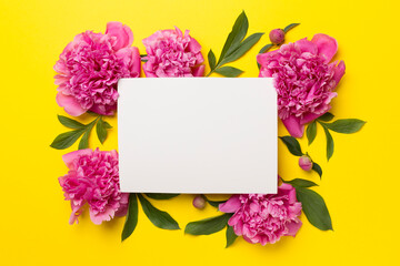 Greeting card mockup with peony flowers on color background, top view