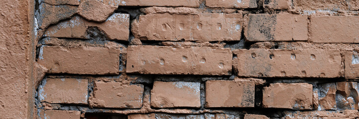 Old brick wall with peeling stucco. Weathered rough wall surface with brickwork. The wall is...