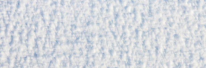 Natural snow texture. The surface of an icy snow crust. Snowy ground. Winter background with snow patterns. Closeup top view. Wide panoramic texture for background and design.