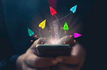 Hand use mobile phone and Group of paper airplanes flying .Unique,out standing.Photo concept inspiration and think different concept.