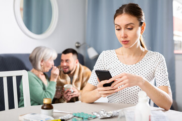 Fototapeta premium Young wife carefully reads the annotation for medicines and checks the information on the Internet