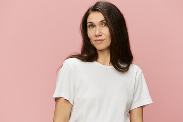 Obraz premium horizontal portrait of a cute attractive woman on a pink background in a clean white tank top smiling pleasantly at the camera
