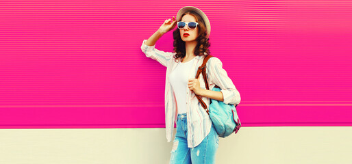 Beautiful young woman posing wearing summer straw hat, backpack on city street on pink background, blank copy space for advertising text