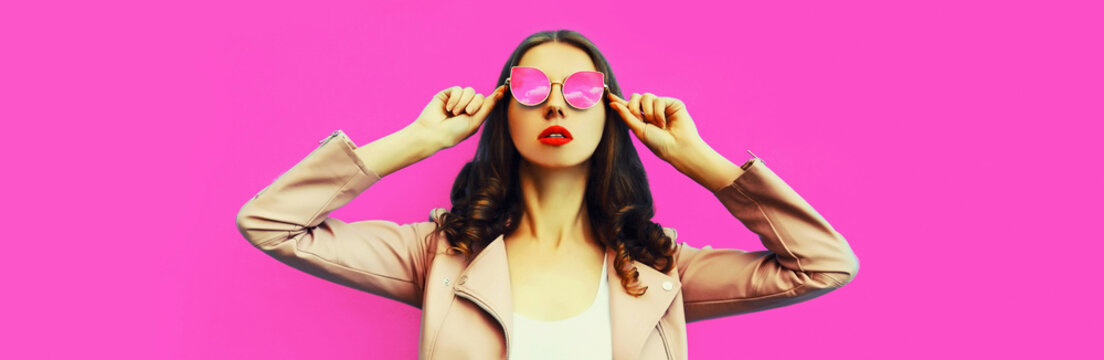 Portrait of beautiful young woman model posing wearing sunglasses on pink background, blank copy space for advertising text