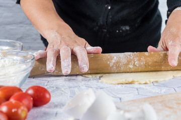 Detail shot of hands kneading with ingredients and cooking instruments around.