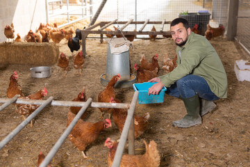 Male farmer feeding chickens in a chicken coop