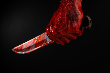 A man with bloody hands brandishes a knife on a black background.  - obrazy, fototapety, plakaty