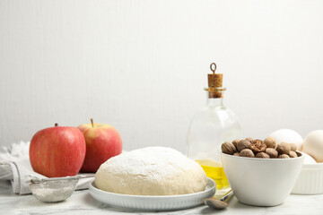 Raw dough, nutmeg seeds and other ingredients for pastry on marble table against white background
