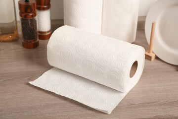 Rolls of white paper towels and other kitchen stuff on wooden countertop