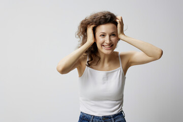 Surprised excited shocked curly beautiful woman in basic white t-shirt touches head open mouth posing isolated on white background. People Emotions Lifestyle. I cant believe it concept. Copy space