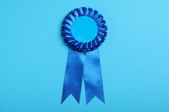 Blue award ribbon on turquoise background, top view