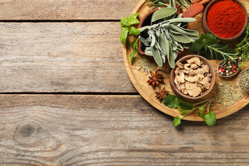 Different herbs and spices on wooden table, top view. Space for text