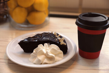 Tasty coffee in takeaway paper cup and dessert on wooden table indoors