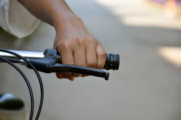 Closeup view of handlebar of bicycle which has hand of kid holding it, soft and selective focus.