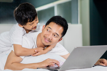Little boy embracing his father while using laptop