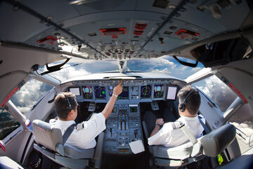 Flight Deck of modern aircraft. Pilots at work. Clouds view from the plane cockpit. - obrazy, fototapety, plakaty