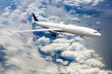 Obraz na płótnie Canvas White passenger plane in flight. Aircraft fly high over the sea.