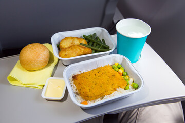 Food in airplane. butter and bread. Hot dish in the aluminum lunch box: fish, chicken, rice and vegetables. Drink: water.