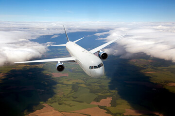 Passenger plane in flight. Aircraft fly high in the sky above green plain. Front view. Left heeling.